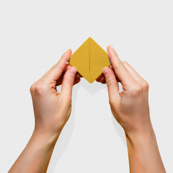 Zwei Hände, die ein goldfarbenes Papier falten